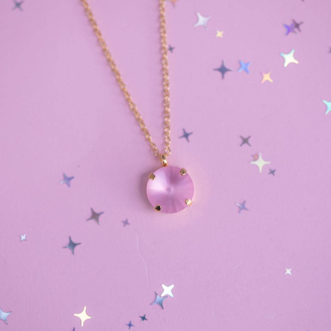 Necklace with a pink pendant on a purple background with star patterns