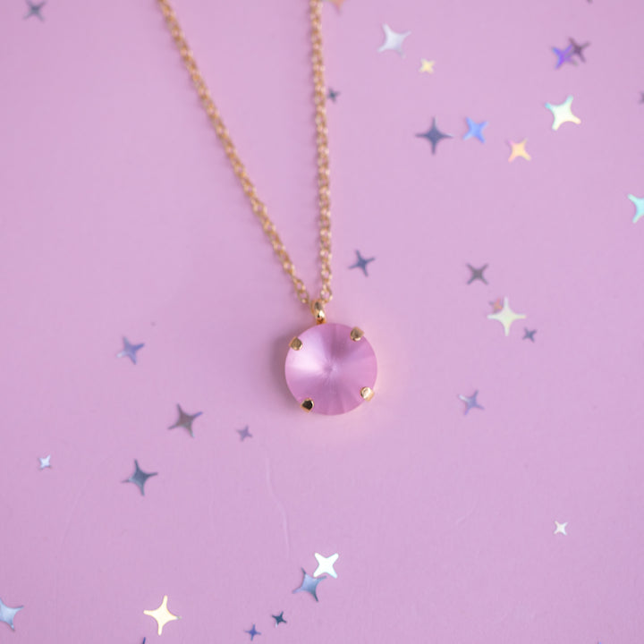 Necklace with a pink pendant on a purple background with star patterns