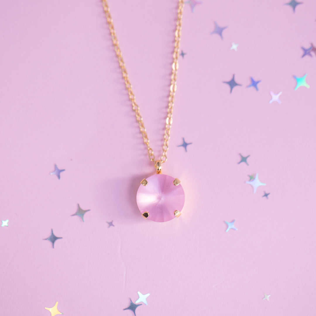 Necklace with a pink pendant on a pink background with star shapes