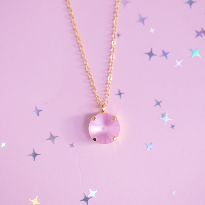 Necklace with a pink pendant on a pink background with star shapes