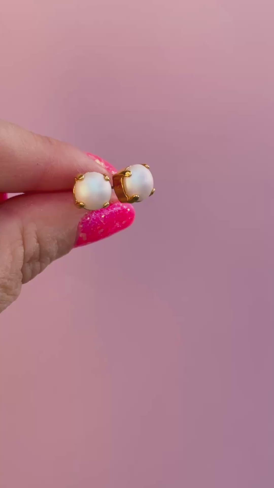 video of pearl stud earrings with a pink background