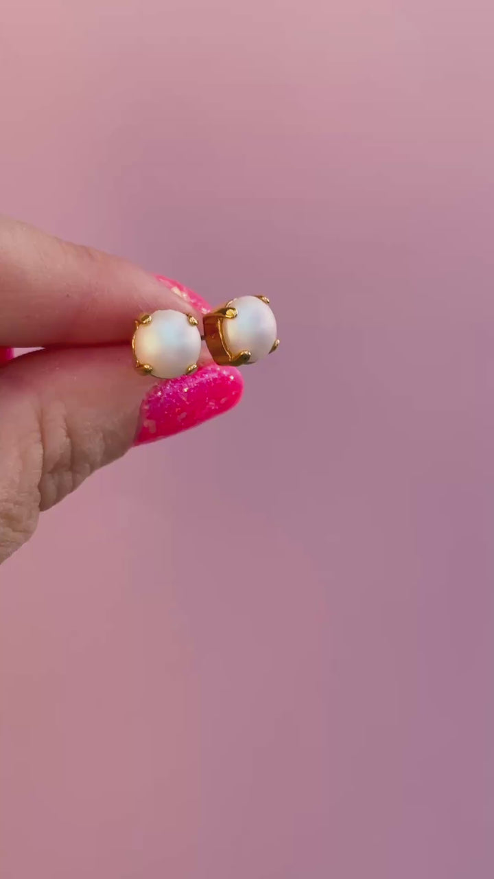 video of pearl stud earrings with a pink background