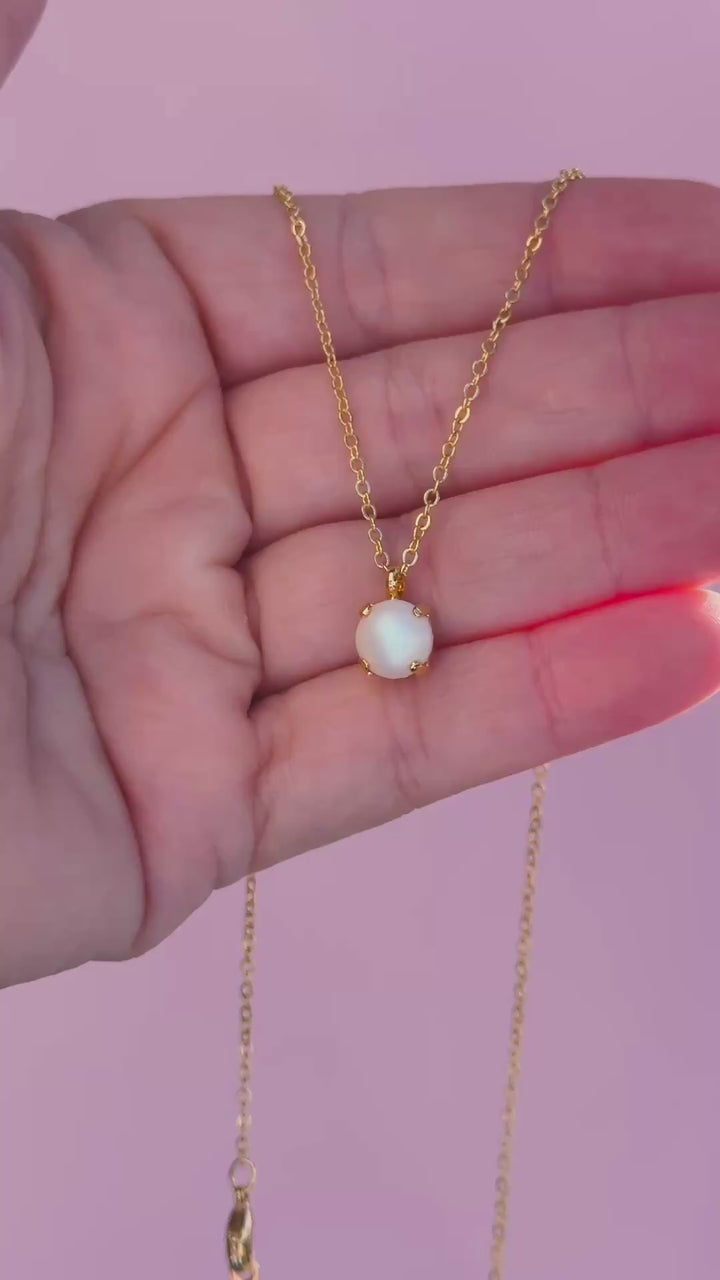 video of a single stone necklace with a white iridescent pearl stone in the middle
