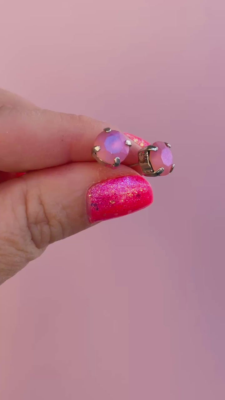 video of stud earrings in a peach color with pink background