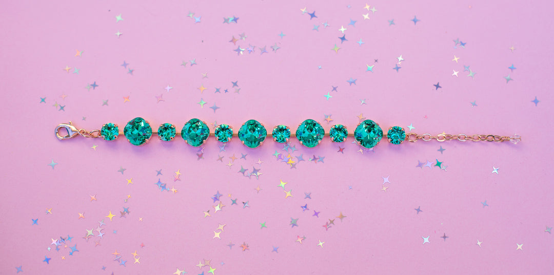 Teal beaded bracelet on a pink background with confetti