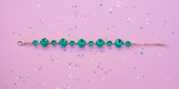 Teal beaded bracelet on a pink background with confetti