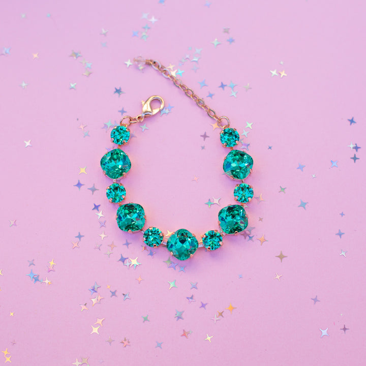 Turquoise crystal bracelet on a pink background with star confetti