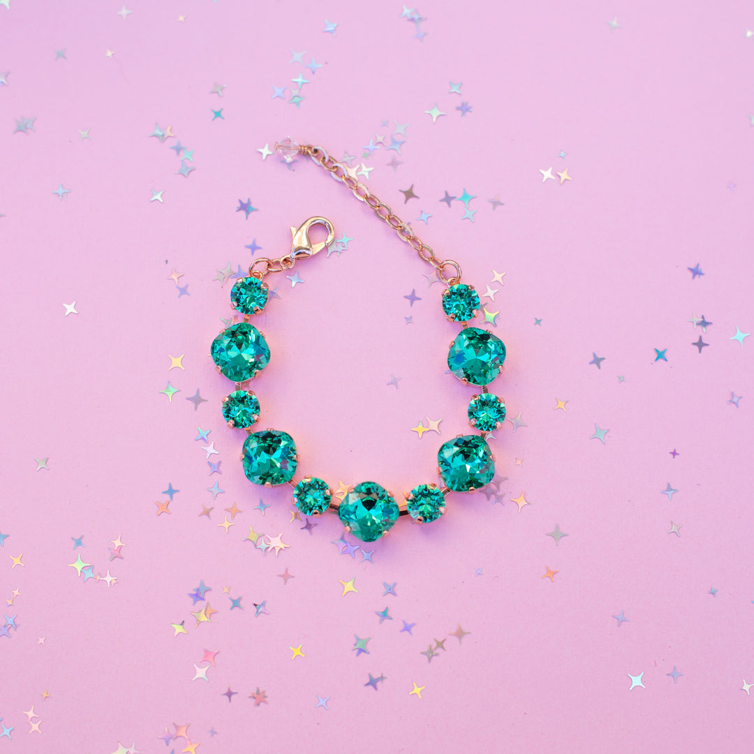 Turquoise bracelet on a pink background with star-shaped confetti