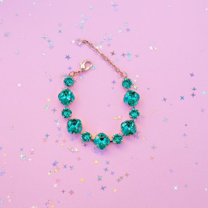 Turquoise bracelet on a pink background with star-shaped confetti