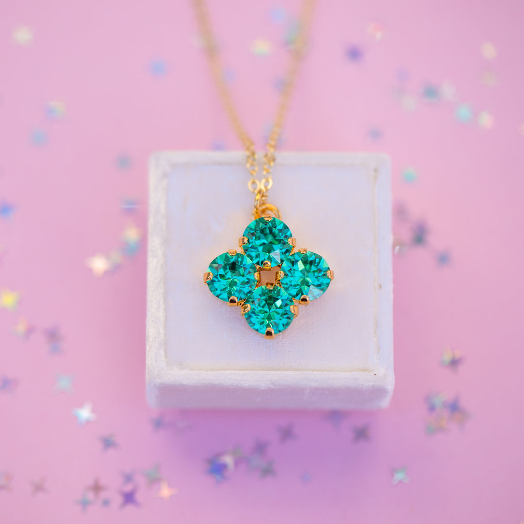 Turquoise pendant necklace on a white box with a pink background