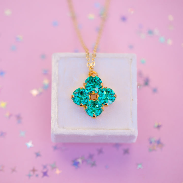 Turquoise pendant necklace on a white box with a pink background