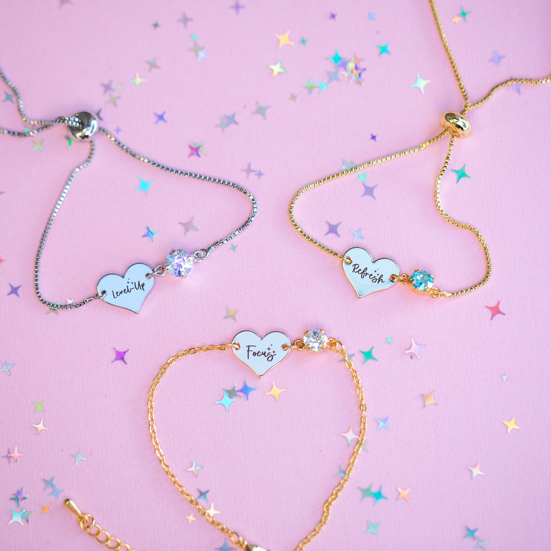 Three heart-shaped bracelets on a pink background with confetti